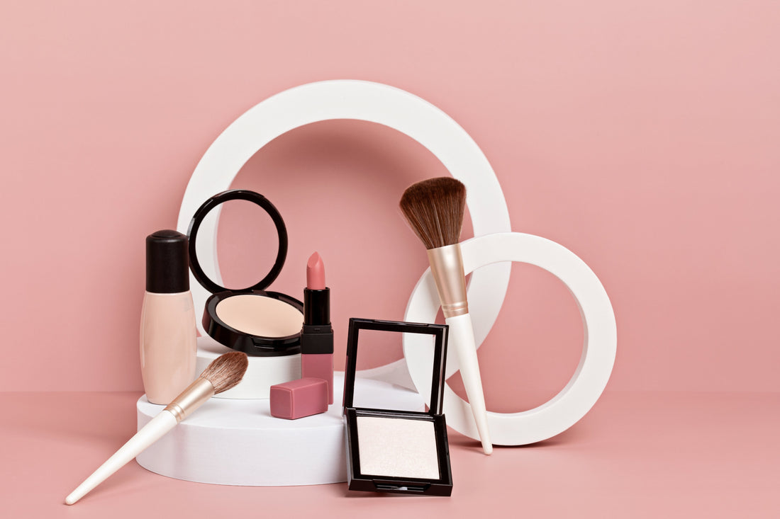 Private label Makeup display on a pink background, includes foundation, powder compacts, lipstick, and brushes.