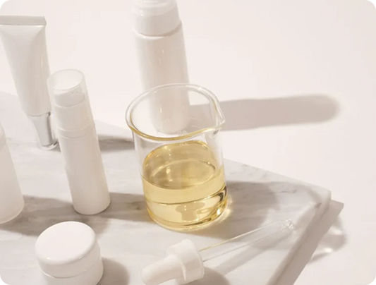 Indigo Private Label skincare formulation setup with lab glassware, droppers, and packaging on a white surface.