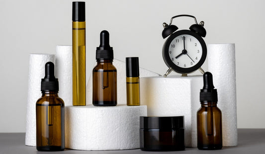 Amber skincare bottles and a black clock on a white display block against a gray background.