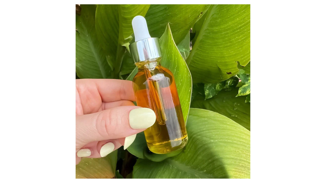 Hand holding an amber dropper bottle of serum against lush green leaves from Indigo Private Label.