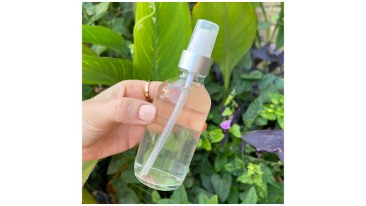  Indigo Private Label balancing face toner bottle held outdoors against garden background.