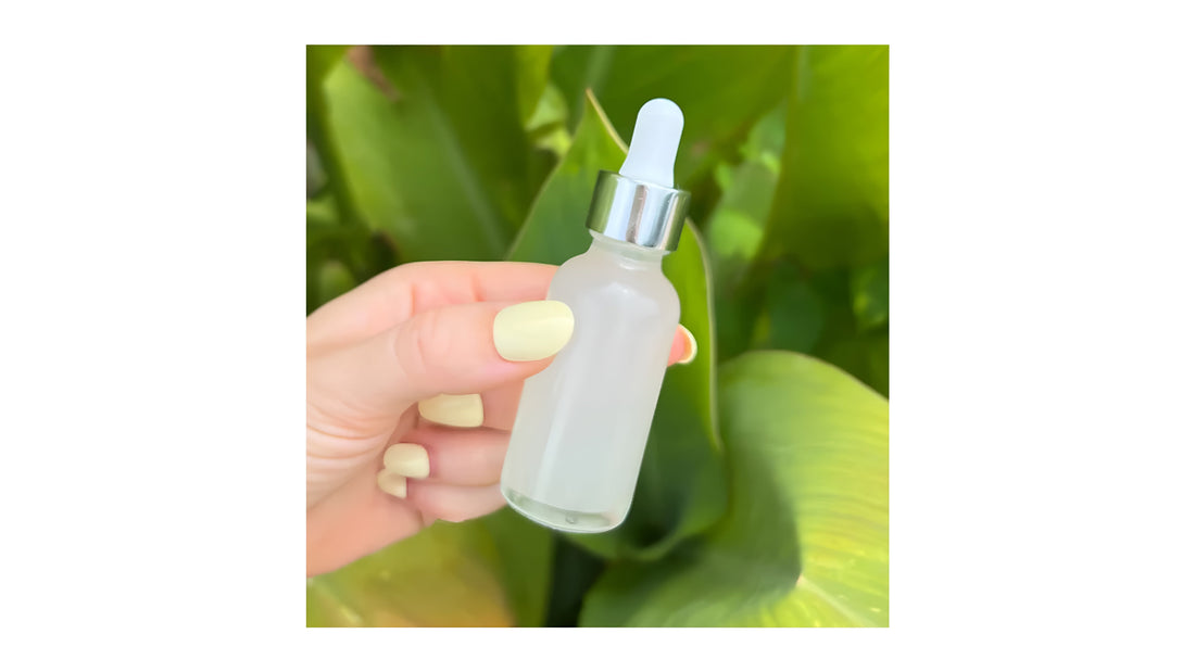 Hyaluronic acid dropper bottle from Indigo Private Label, held against lush green leaves.