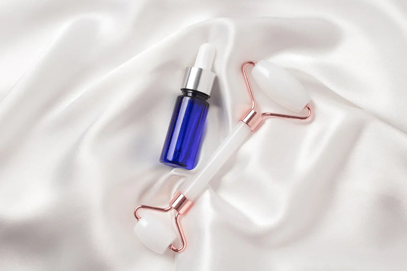 Indigo Private Label GHK-Cu Peptide Serum bottle with a facial roller on white satin.
