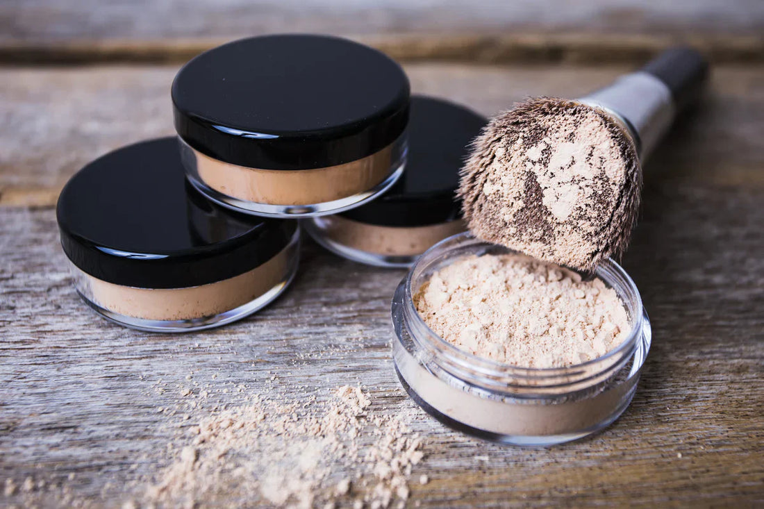 Indigo Private Label loose mineral powder jars with a makeup brush on a rustic wood surface.
