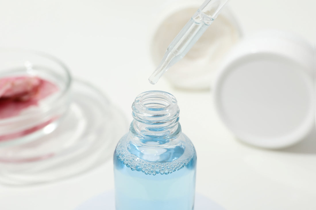 Close-up of a dropper dispensing copper peptide serum into a small glass bottle. 