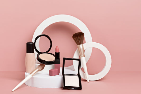 Private label Makeup display on a pink background, includes foundation, powder compacts, lipstick, and brushes. 