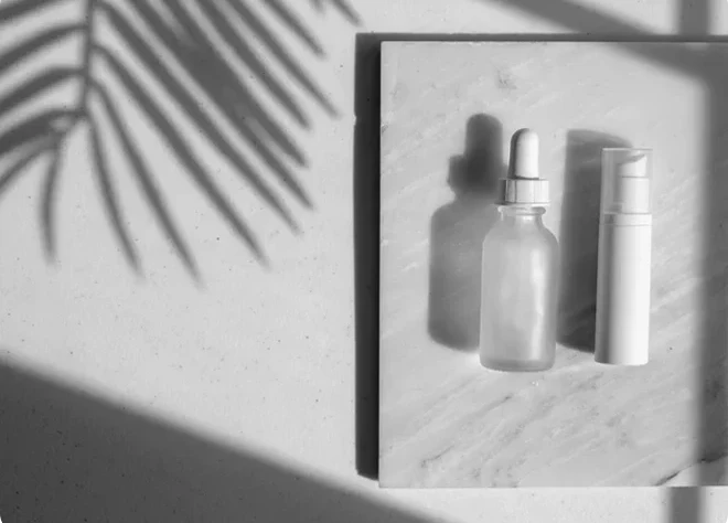 Indigo Private Label skincare bottles on a stone surface with soft palm leaf shadows.