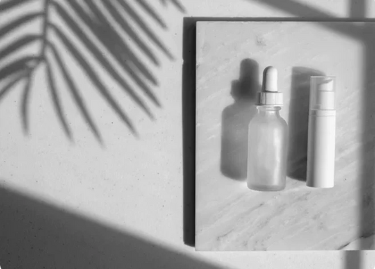 Indigo Private Label skincare bottles on a stone surface with soft palm leaf shadows.