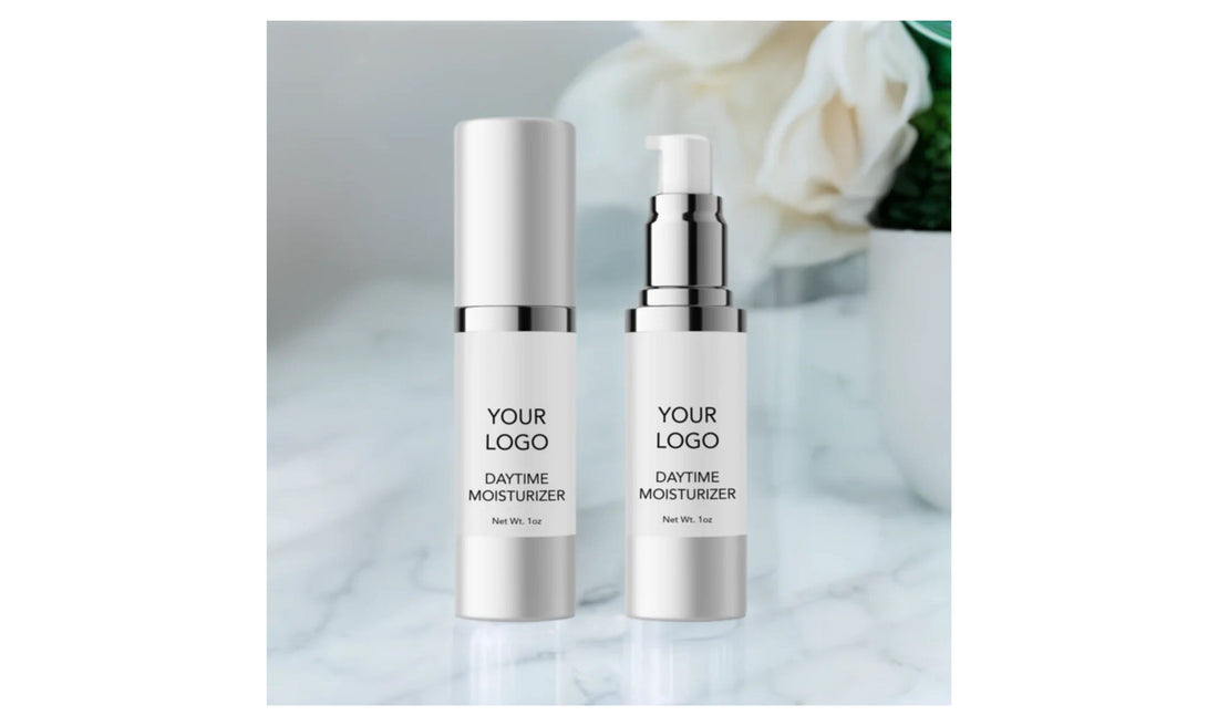 Indigo Private Label daytime moisturizer in two white pump bottles on marble with blurred flowers behind.